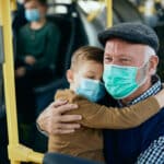 Fürsorglicher großvater mit enkel, der beim pendeln mit dem bus gesichtsmasken trägt von @ Drazen Zigic