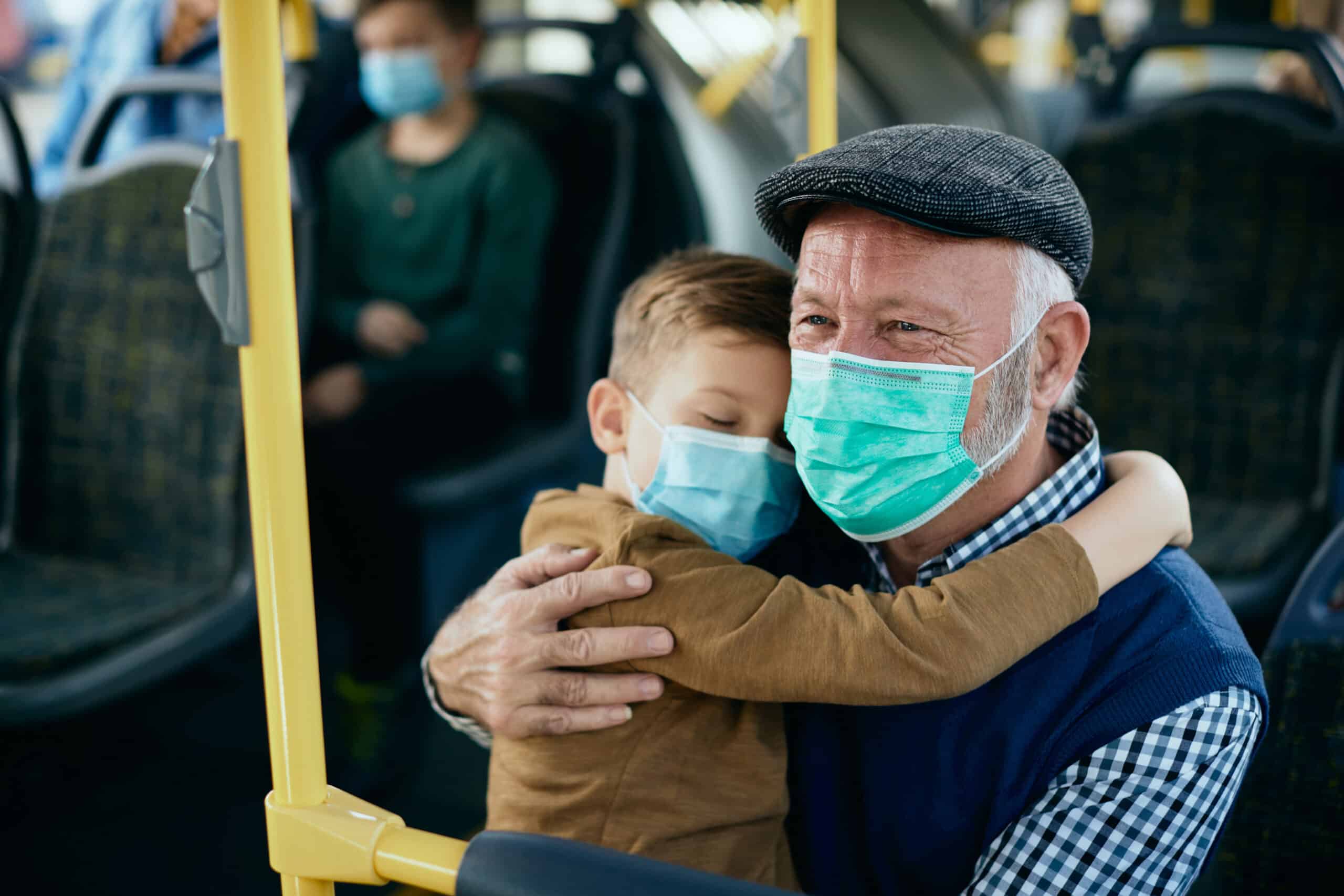 Fürsorglicher großvater mit enkel, der beim pendeln mit dem bus gesichtsmasken trägt von @ Drazen Zigic